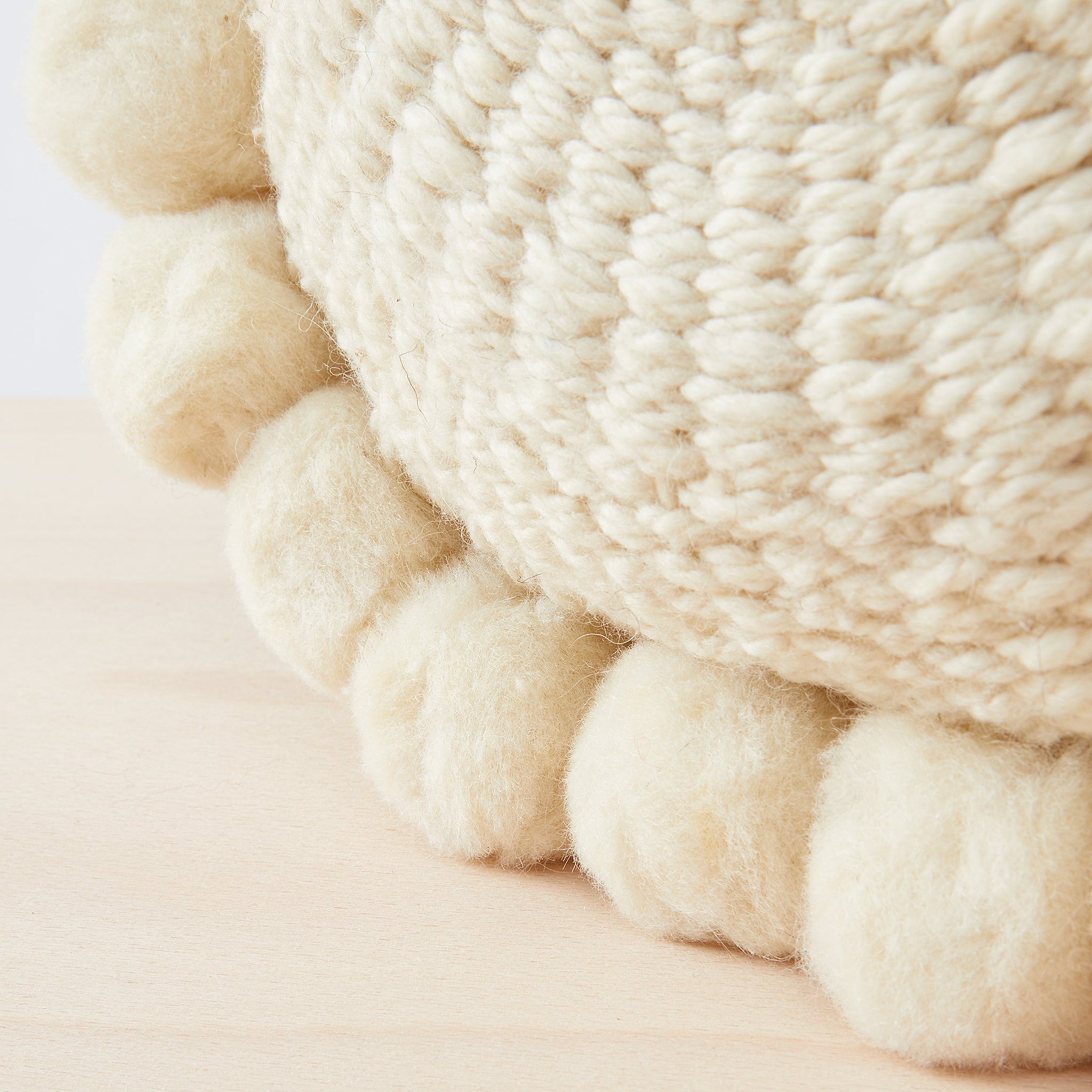 Detail of Po Pom cushion in 100% virgin wool with pom poms.